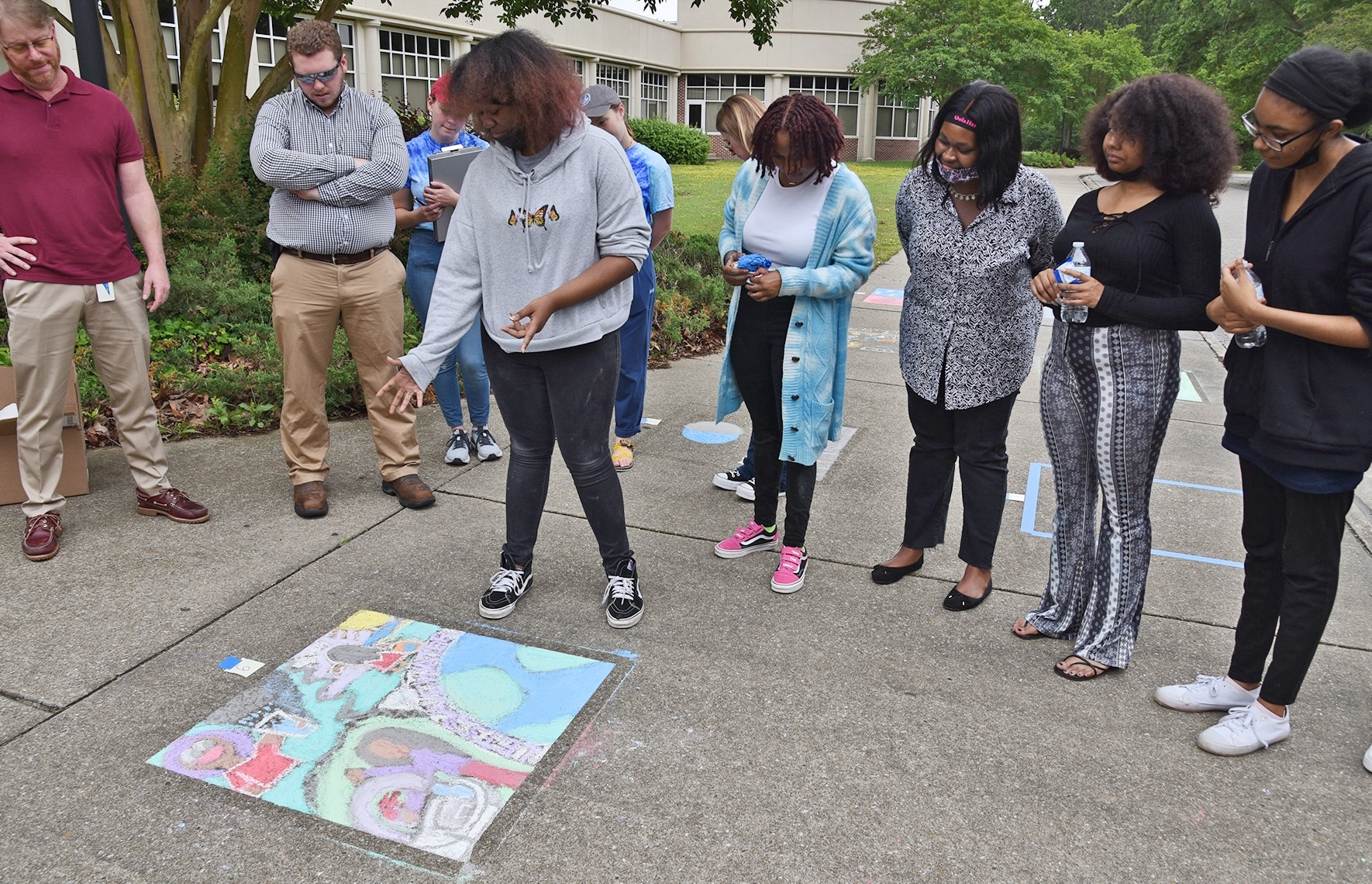 We offer a scholarship program based on a water-themed chalk art contest. Here, a student explains their artwork to the judge panel.